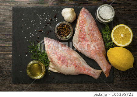 Sea perch on black board. Sea bass on black board with ingredients for cooking 105395723