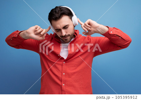 charming positive 30s man in red shirt with wireless white headphones 105395912