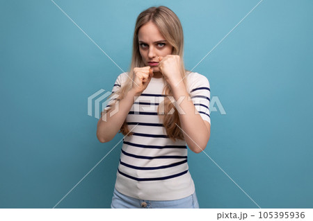 close-up photo of a strong girl in casual clothes showing superiority with muscles on a blue close-up photo of a strong girl in casual clothes showing superiority with muscles on a blue 105395936