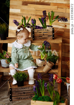Adorable little girl playing gardener planting spring flowers in pots. Adorable little girl playing gardener planting spring flowers in pots. 105396672