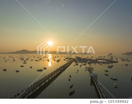 aerial view fishing boats on the beach at Chalong pier in sunrise..Sunrise with sweet yellow color light rays and other atmospheric effects..colorful reflection of sunrise in the sea background..d. aerial view fishing boats on the beach at Chalong pier in sunrise..Sunrise with sweet yellow color light rays and other atmospheric effects..colorful reflection of sunrise in the sea background..d. 105399982