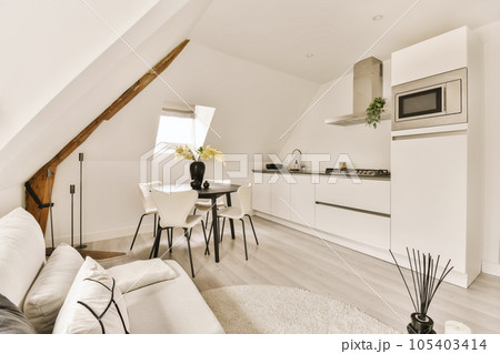 a living room and kitchen area in a loft apartment with white walls, hardwood flooring and light wood floors a living room and kitchen area in a loft apartment with white walls, hardwood flooring and light wood floors 105403414