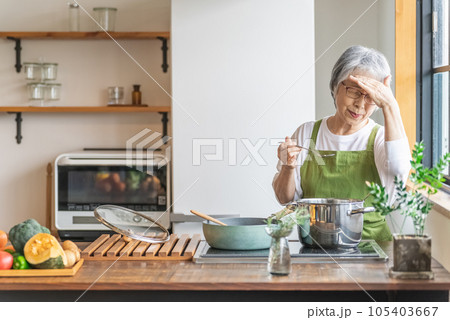 家のキッチンで料理を作るアジア人のシニア・高齢者女性（認知症・悩む） 105403667