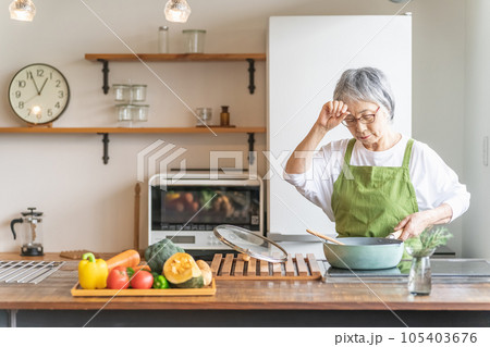 家のキッチンで料理を作るアジア人の高齢者女性（認知症・悩む） 105403676