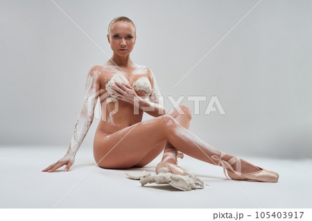 Nude ballerina in gypsum sitting on the floor of studio 105403917