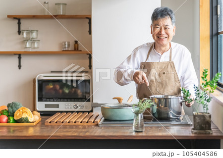 家のキッチンで鍋を使って煮込み料理を作るアジア人の高齢者男性(笑顔) 家のキッチンで鍋を使って煮込み料理を作るアジア人の高齢者男性(笑顔) 105404586