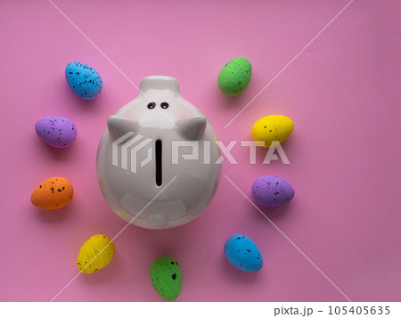 Piggy bank surrounded by colorful Easter eggs on pink background. Piggy bank surrounded by colorful Easter eggs on pink background. 105405635