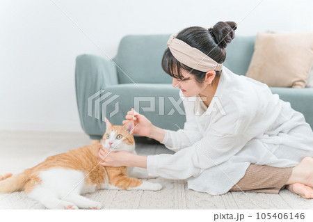 綿棒を使って猫の耳掃除をする飼い主のアジア人女性 105406146