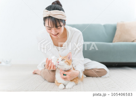 猫に目薬をさそうとする飼い主の女性（投薬・病気） 105406583