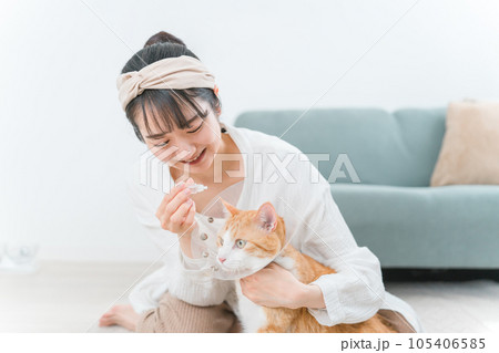 猫に目薬をさそうとする飼い主の女性（投薬・病気） 105406585