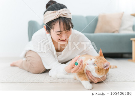 猫に目薬をさそうとする飼い主の女性(投薬・病気) 猫に目薬をさそうとする飼い主の女性(投薬・病気) 105406586