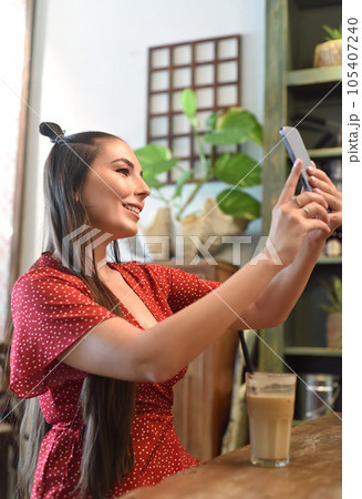 Young woman taking selfie in a coffee shop 105407240