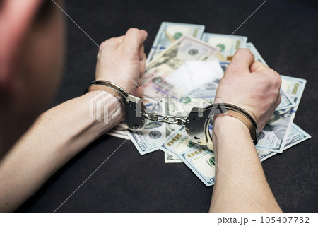 Man in handcuffs with money and drugs on dark background. Man in handcuffs with money and drugs on dark background. 105407732
