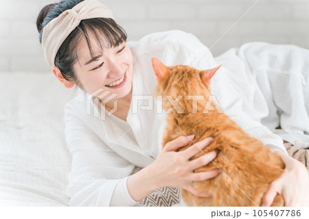 家のベッドルーム・寝室で猫・ペットを可愛がる飼い主の女性(話しかける) 家のベッドルーム・寝室で猫・ペットを可愛がる飼い主の女性(話しかける) 105407786