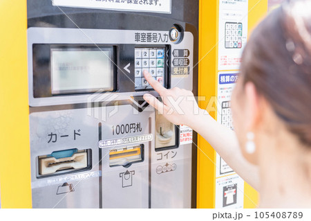 コインパーキング・駐車場のお金を入れる女性 105408789