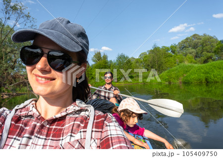 Man and woman couple, child 6 years old, selfies are happy in family kayak trip rowing boat on the river, water hike, a summer adventure. Eco-friendly and extreme tourism, active and healthy lifestyle 105409750