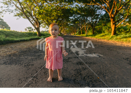 Beautiful infant girl in outdoor with sunset tones. Cute baby in pink dress in park. Beautiful infant girl in outdoor with sunset tones. Cute baby in pink dress in park. 105411847