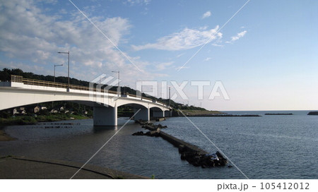 夏の穏やかな日本海と青空と白い雲と海に架かる真白な夕日ライン橋 105412012
