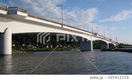 夏の穏やかな日本海と青空と白い雲と海に架かる真白な夕日ライン橋 105412159