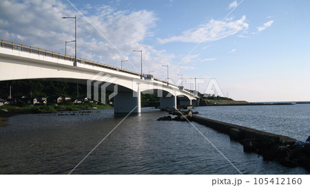 夏の穏やかな日本海と青空と白い雲と海に架かる真白な夕日ライン橋 105412160