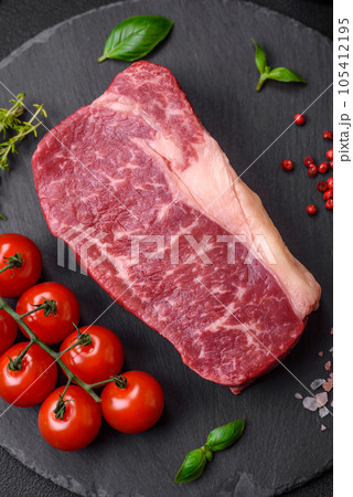 Fresh raw beef striploin steak with salt, spices and herbs 105412195