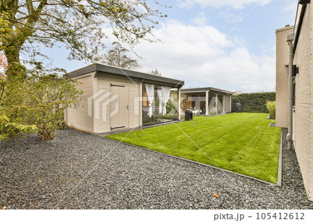 a backyard area with a shed and green grass in the yard is surrounded by trees, shrubs and bushes on both sides 105412612