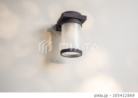 Outdoor cylinder lamp with tree leaves shadow on concrete wall Outdoor cylinder lamp with tree leaves shadow on concrete wall 105412869