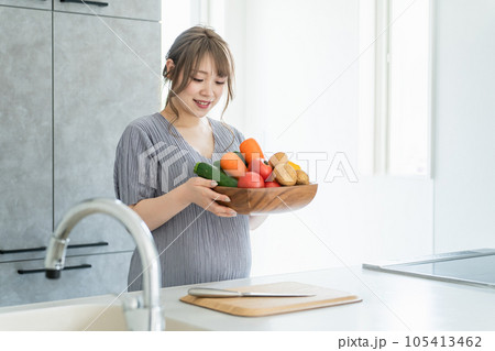 キッチンで野菜を持つアジア人女性・妊婦・プレママ キッチンで野菜を持つアジア人女性・妊婦・プレママ 105413462