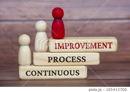 Red wooden doll and other white wooden dolls moving towards continuous process improvement. 105413700