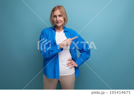 blond middle-aged woman with a bob haircut points her finger to the side in a studio background blond middle-aged woman with a bob haircut points her finger to the side in a studio background 105414675