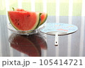 皿に入れられた二切れのすいかと傍らにうちわ 105414721
