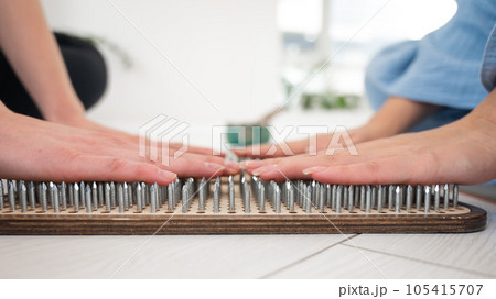 Close-up of two women's hands on sadhu boards. Nailing practice. 105415707