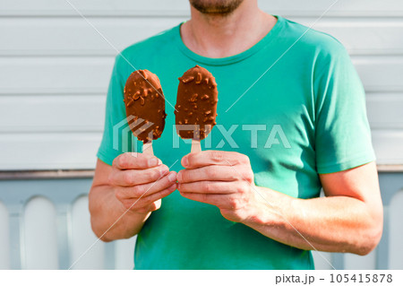 man hands holding two ice creams. guy holding ice cream on blue background man hands holding two ice creams. guy holding ice cream on blue background 105415878