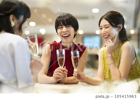 女子会　イメージ　シャンパングラスを持って談笑する若い女性たち　 105415963
