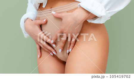 A woman in underwear holds her hands to her lower abdomen. Close-up. The concept of gynecology and women's health 105419702