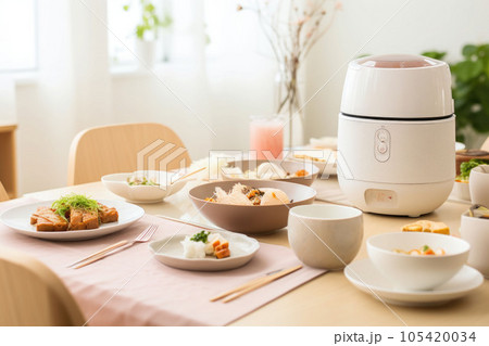 A minimalist bright kitchen with a rice cooker and dishes on top of the dining table. Generative AI 105420034