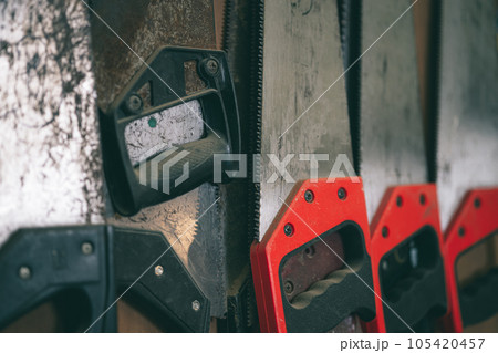 closeup old used rust hand saw sharp teeth for heavy duty wood cut home diy tool hang in workshop. 105420457