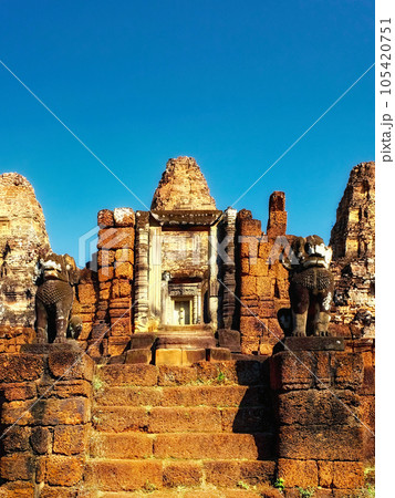 An image displaying a blue, cloudless sky over the ancient Khmer ruins and stone steps of East Mebon. 105420751