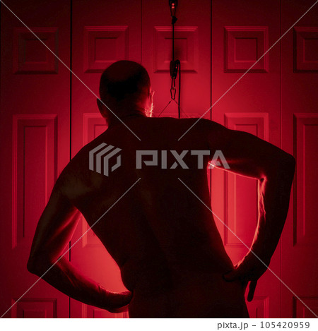 silhouette of a senior athletic, man torso standing in front of the red light therapy panel, home setup for treatment 105420959