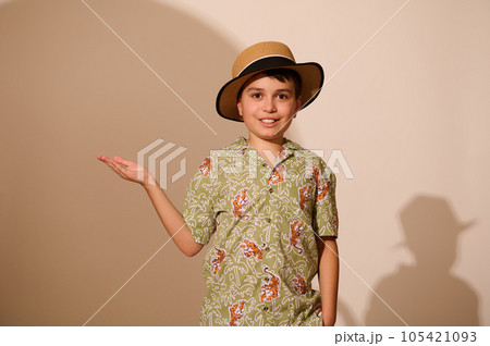 Latin American charming teenage boy tourist traveler in summer clothes, holding imaginary copy ad space on hand palm up 105421093