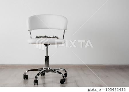 Chair with barbed wire near white wall, space for text. Hemorrhoids concept 105423456