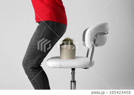 Woman sitting down on chair with cactus against white background, closeup. Hemorrhoids concept 105423458