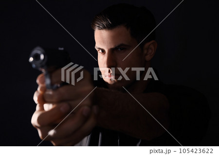 Professional killer with gun on black background 105423622
