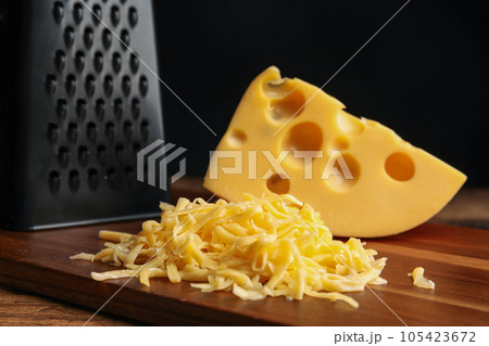 Tasty grated cheese on wooden table, closeup 105423672