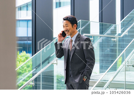 オフィスでスマホで通話する中年ビジネスパーソン オフィスでスマホで通話する中年ビジネスパーソン 105426036