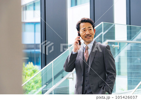 オフィスでスマホで通話する中年ビジネスパーソン 105426037