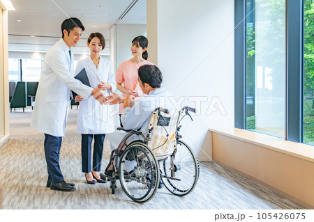 車椅子のシニア男性患者と会話する医師・看護師 105426075