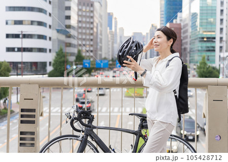 髪を気にしながら、自転車用ヘルメットを被るアラフィフ女性 105428712