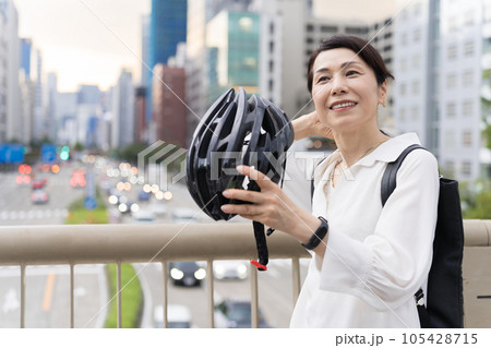 髪を気にしながら、自転車用ヘルメットを被るアラフィフ女性 髪を気にしながら、自転車用ヘルメットを被るアラフィフ女性 105428715