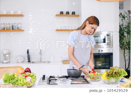 beautiful young woman trying cook healthy food salad vegetables mix at home kitchen 105429529